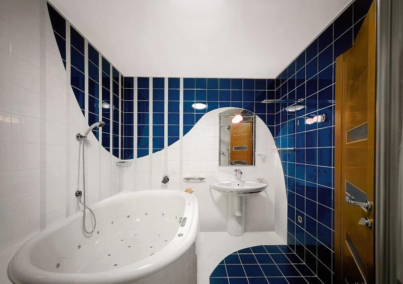 Синяя керамическая плитка и плавные линии скрывают пространство,а заодно и белую ванну.