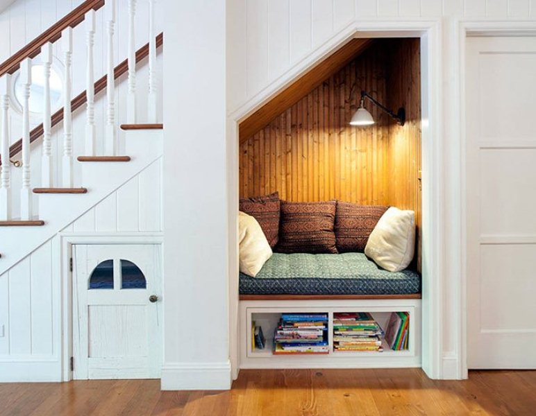 Небольшой диванчик в нише под лестницей для чтения