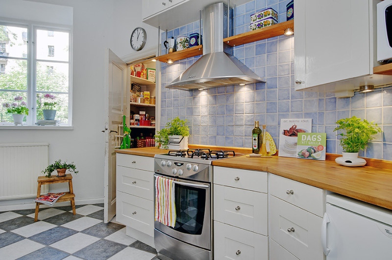 Дизайн кухни в скандинавском стиле с шахматным полом, с фартуком нежного-голубого цвета и и красочным декором