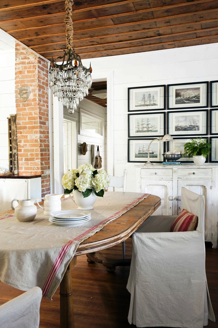 Дизайн столовой с деревянным столом,красивой старинной люстрой и картинами морской тематики