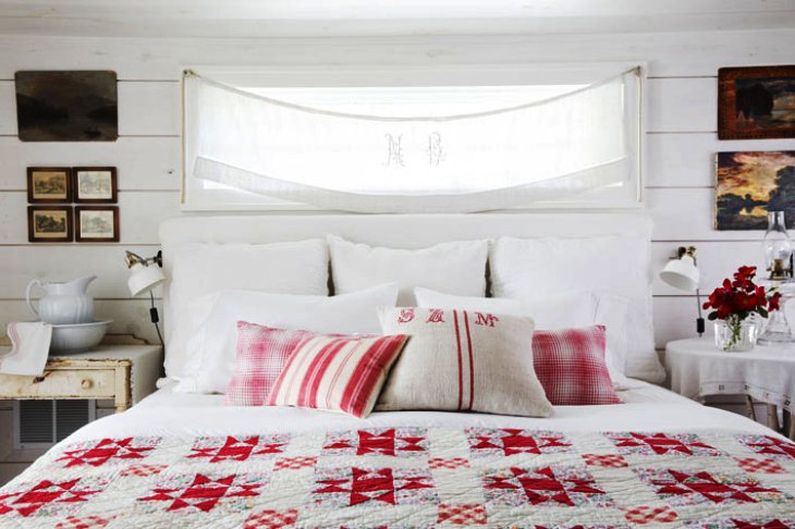 Уютная деревенская обстановка спальни в стиле кантри с обилием подушек на большой кровати