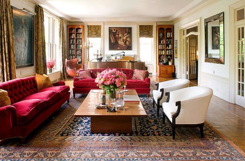 Интерьер элегантной гостиной с шикарными мягкими диванами красного цвета и белыми креслами