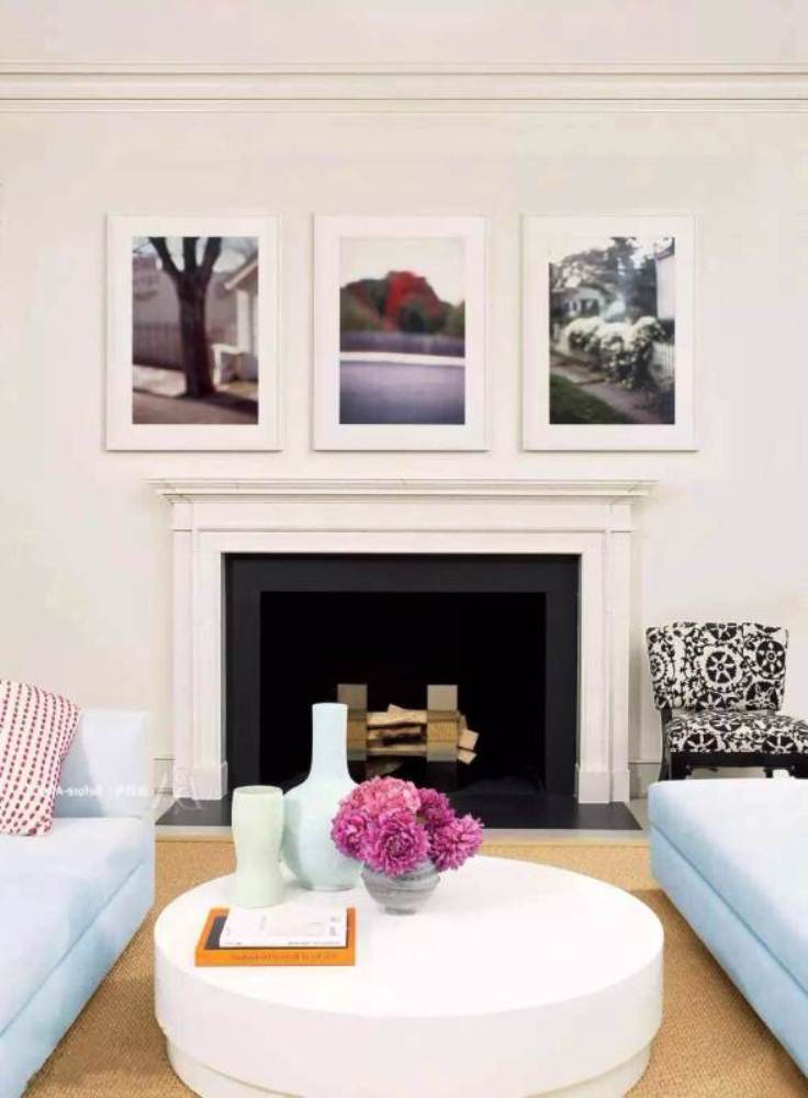 Холодная палитра оттенков белого цвета, круглый кофейный столик и камин в дизайне гостиной