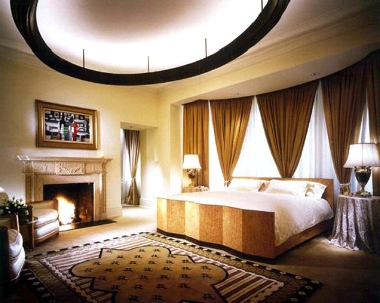 Очень уютная спальня с камином, широкой кроватью и огромной круглой люстрой