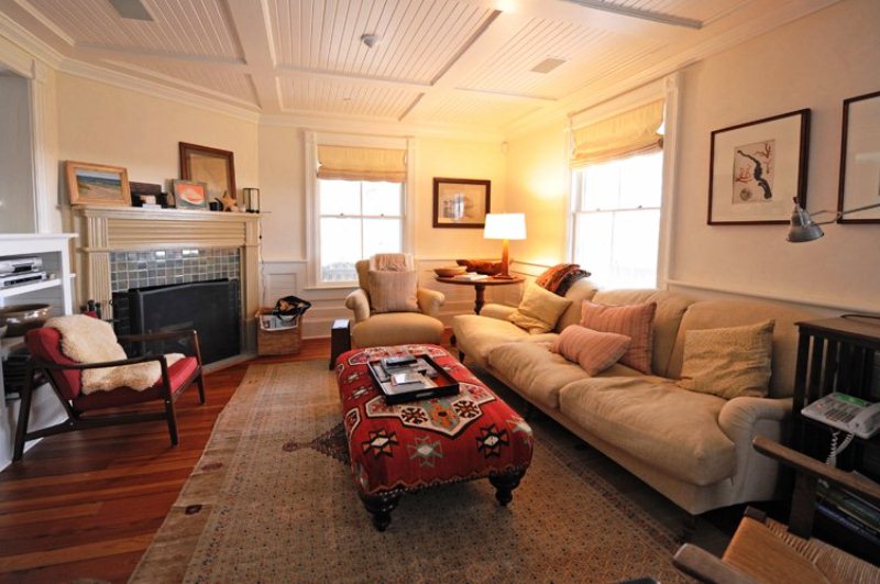 Небольшая гостиная с камином, деревянным потолком белого цвета и множеством удобных мест для отдыха