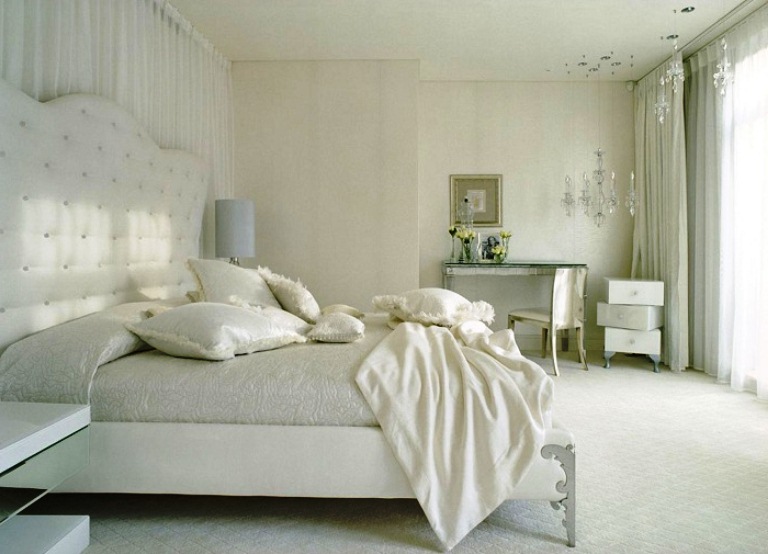 Нежная белоснежная кровать с красивым изголовьем, подушки с бахромой и креативная тумбочка в классическом дизайне спальни