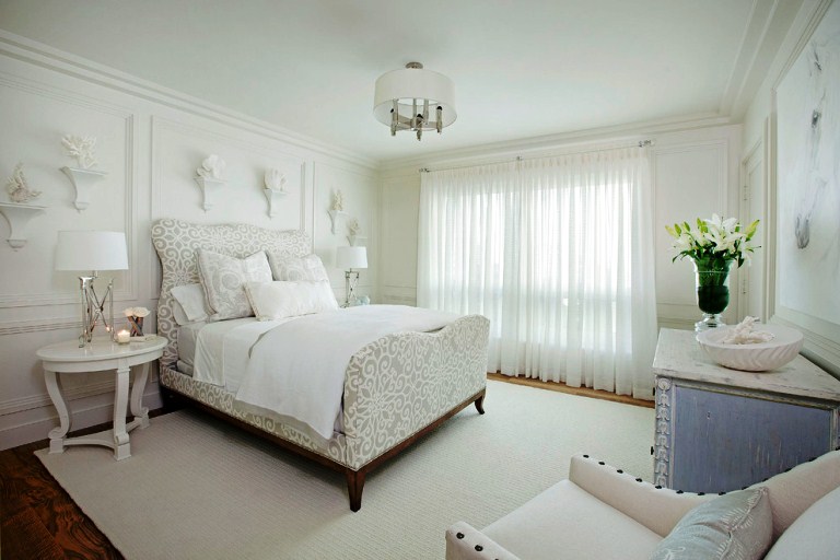 Интерьер просторной спальни с белых тонах с креативным прикроватным столиком и винтажным комодом