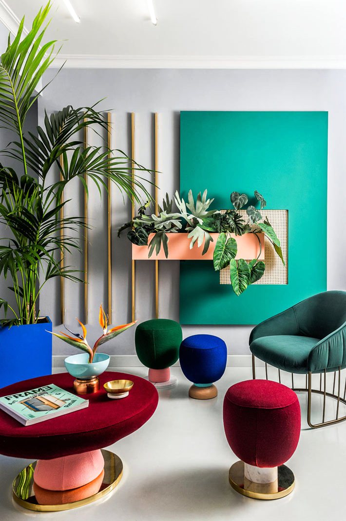 Современный дизайн квартиры с огромными растениями с яркими пуфиками и акцентной стеной зеленого цвета