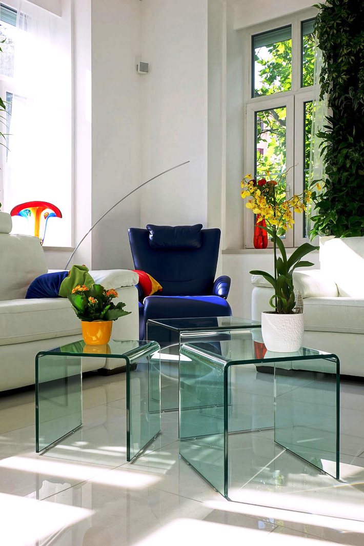 Дизайн прихожей с живой стеной, синим креслом и стеклянными табуретками 